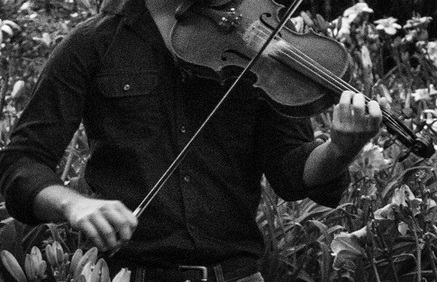 Black and white photograph of a violin being held in a garden